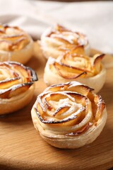 Freshly baked apple roses on wooden board, closeup