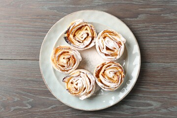 Freshly baked apple roses on wooden table, top view