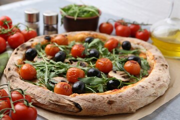 Tasty pizza with cherry tomatoes, black olives, mushrooms and arugula on grey table, closeup
