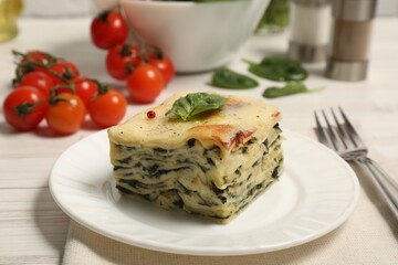 Piece of delicious spinach lasagne served on white wooden table, closeup