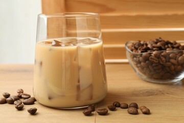 Coffee cream liqueur in glass and beans on wooden table, closeup
