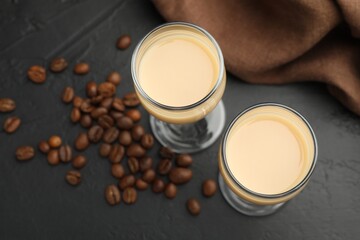 Coffee cream liqueur in glasses and beans on black table, above view
