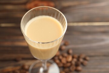 Coffee cream liqueur in glass and beans on table, closeup. Space for text