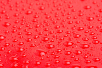 Red plastic with water drops macro photo. Red abstract background.