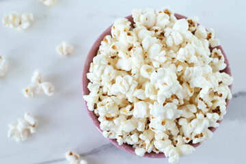 Popcorn in a bowl isolated on a white marble background. Top view. Close-up.