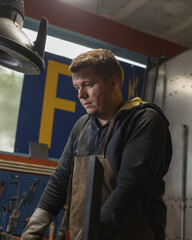 Portrait of male welder in protective gear working in metal workshop.