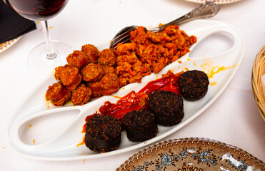 Popular Spanish tapas - sliced fried blood sausage, chorizo, traditional picadillo and baked hot...
