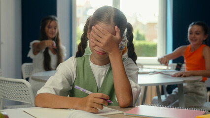 Caucasian sad worried crying little girl pupil schoolgirl in school classroom upset teen student child kid suffer bullying studying problem cruel children classmates abuse bully mock throwing papers