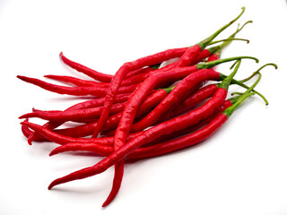 A stack of long red chilies rests against a clean white background, highlighting their vibrant hue and glossy skin
