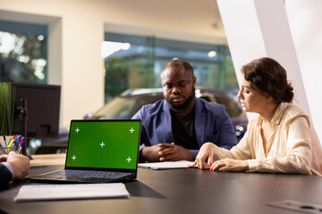 Sales executive in dealership using isolated screen laptop, negotiating price and extra car features to help solidify deal. Agent persuading hesitant customers to buy vehicle using chroma key notebook