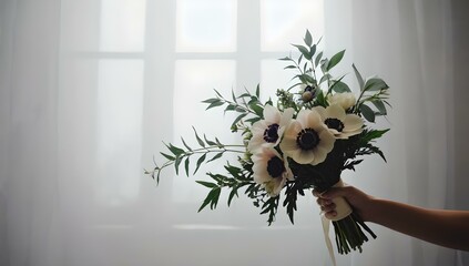 Bride holding a bouquet of white anemones and greenery, captured against a soft background with minimalistic styling. The bouquetвЂ™s simple elegance, combined with soft light, enhances the romantic, 