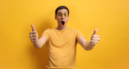 Happy and cheerful young man gesturing thumbs up