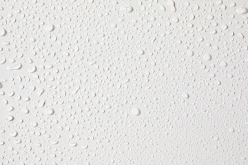 Water droplets cover a smooth white surface after a gentle rainfall in a serene, indoor...