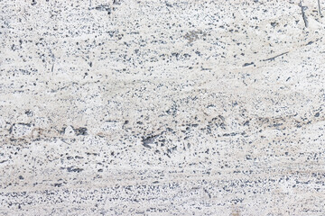 Straight down view of a large slab of light porous stone floor.