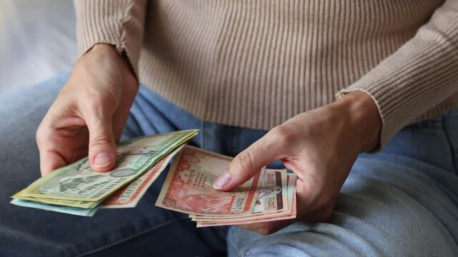 Close up view of woman's hands holding Nepalese rupee (NPR) cash money banknotes. Concept of saving money for retirement, cash settlement, financial success, literacy and income planning in Nepal.