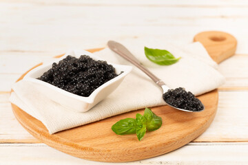 Bowl with black caviar on on wooden table