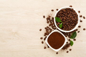 Roasted coffee beans with leaves on wooden background,top view