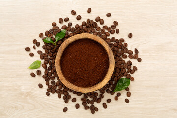 Roasted coffee beans with leaves on wooden background,top view