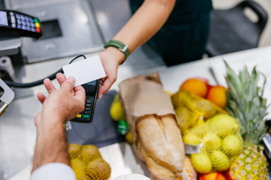 Customer paying with contactless credit card at supermarket checkout