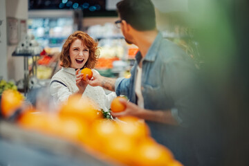 Happy couple choosing oranges in supermarket produce section