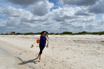 Woman runs and plays on the beach with a ball on her arm