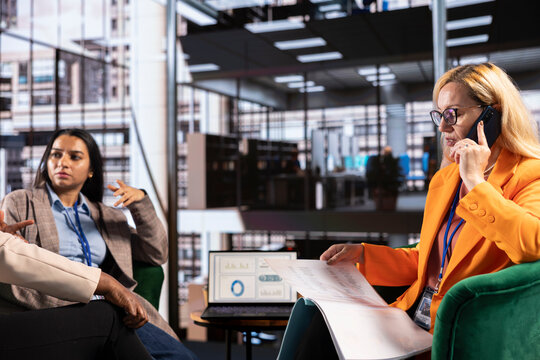 Female CEO on a phone call discussion with a business adviser speaking about potential profit increase in a meeting. Multicultural team sharing ideas, manager calling consultant.