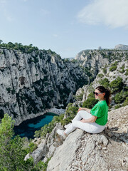 Naklejka premium A girl sits on the edge of a mountain near the sea and a landscape of nature.