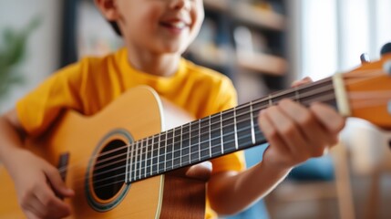 Obraz premium Close-up of a joyful boy strumming an acoustic guitar indoors