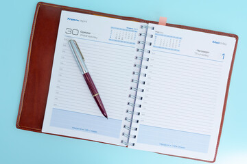 Open planner with a pen on a blue background