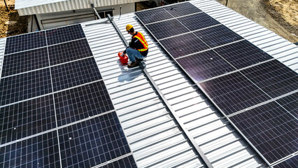 A worker wearing safety gear installing solar panels on a rooftop with nearby housing units in the background, emphasizing renewable energy, sustainability, and efficient solar power implementation