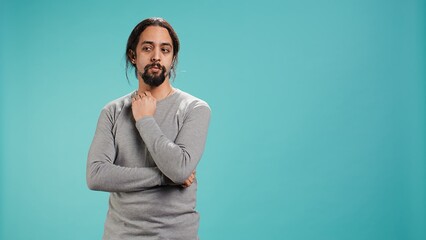 Portrait of man scratching neck with fingers, listening for unfamiliar sound, concentrating on...
