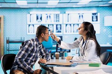 Fototapeta premium Medic expert uses a thermometer to find the right diagnostic and symptoms, showcasing modern healthcare practices to support patients on medical insurance services. Fever measurements.