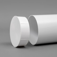 White plastic pipe with a plug on a gray background. Round shape.