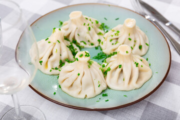 There is portion of khinkali on plate - national Georgian dish made of dough and meat. Boiled dough balls with minced meat filling.