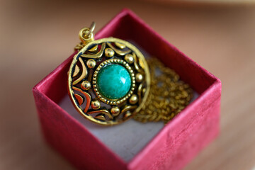 Green stone on a brooch on a chain in a box.
