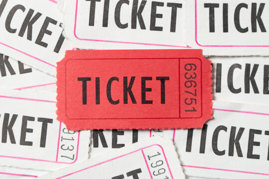 Single red vintage admission ticket on top of many white stub tickets, for movie theme design