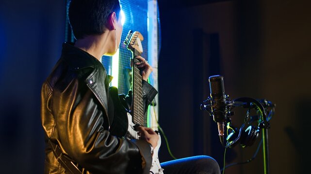 Pop star in leather jacket performs a song in a live concert hall, powerful artist with an amazing melodic voice. Bold grunge musician singing alternative music for a show. Camera A.