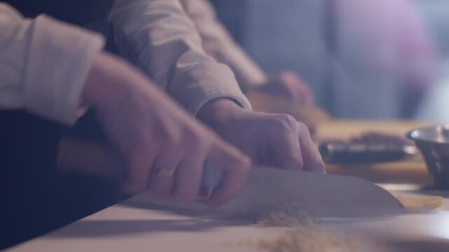 Cheerful woman in headband chopping garlic with knife in kitchen