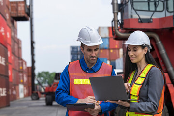 Two logistics workers man and woman discuss operations at a busy shipping container yard.