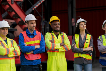 Team logistics workers in high visibility safety gear and hard hats discuss operations at a busy shipping container yard. Team multi nationality working together on site container warehouse.