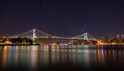 Obraz premium Bay Bridge lit up at night against city skyline reflection