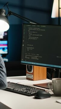 Vertical Video African american male programmer working on cloud computing with an algorithm, writing code for optimization on terminal window. IT specialist inserts html code, server security. Camera