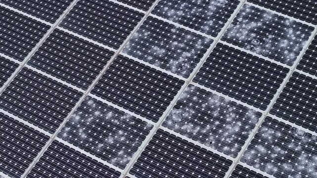 AERIAL, CLOSE UP: Set of solar panels severely damaged by a hailstorm. Spiderweb patterns spread across multiple photovoltaic cells. Vulnerability of renewable energy infrastructure to extreme weather