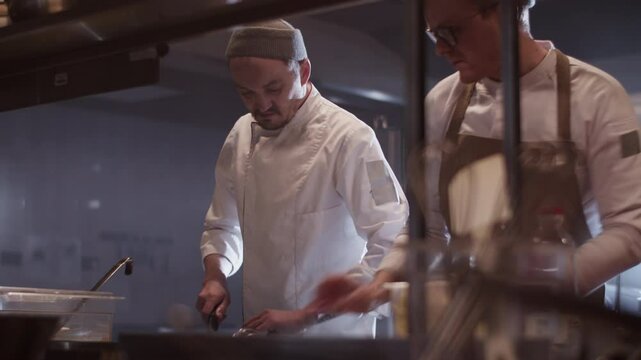 Men chefs preparing dishes while working in kitchen restaurant