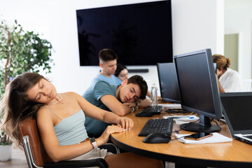Tired young female employee engaged in programming or data analysis in coworking space dozing off...