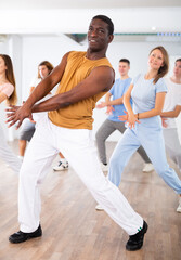 Obraz premium Smiling females and males doing dance workout during group classes in fitness center