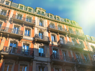 Fototapeta premium Sunlit traditional European building showcases ornate balconies and vibrant facades under a clear blue sky.
