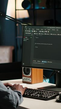Vertical Video Black man programmer manages code and scripts in artificial intelligence and machine learning on dual monitors computer setup. Male freelancer uses pc to guarantee cyber security