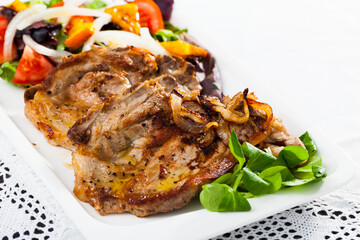 Tasty cooked fried pork chops with salad of fried orange, lettuche and tomatoes