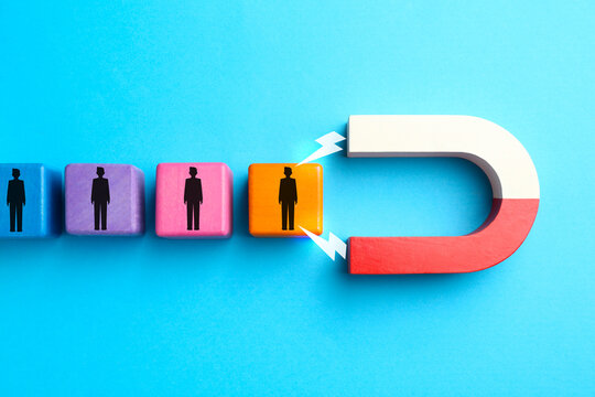 Magnet attracting colorful cubes with human figures on light blue background, top view. Recruitment or customer acquisition